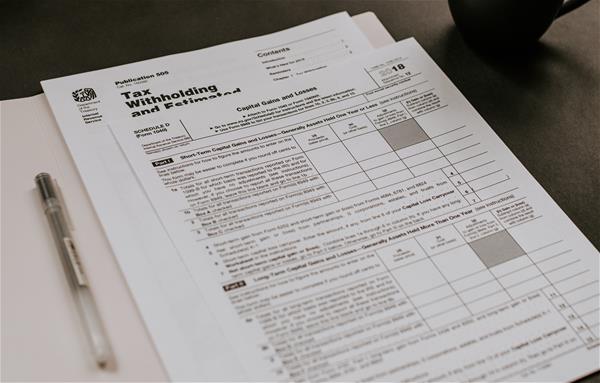kelly-sikkema-1484280-unsplash Pile of tax documents with a pen.